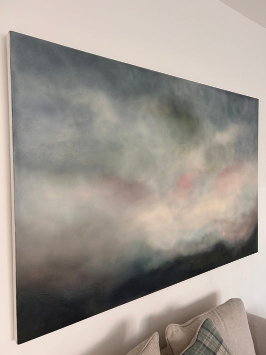 Abstract painting on a white wall with a neutral-colored sofa in the background